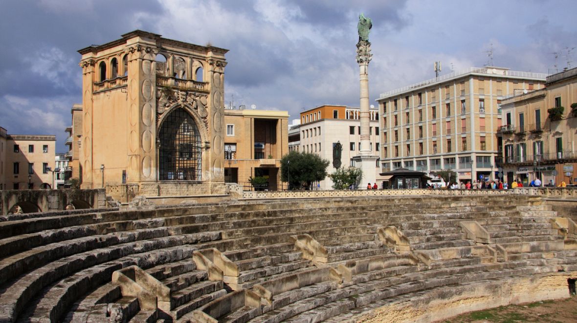 Římský amfitátr, budova patřící radnici a sloup s patronem města