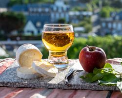 Tradiční produkty Normandie – sýr a sklenka jablečného cideru