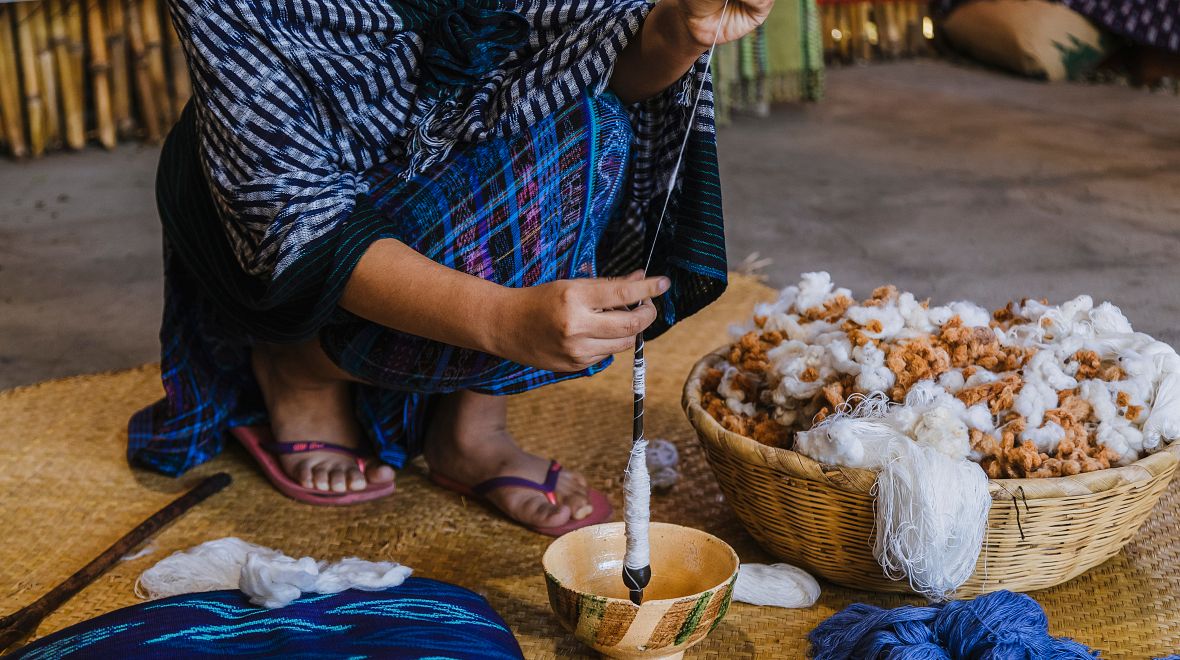 Žena vyrábí typický místní oděv z bavlny