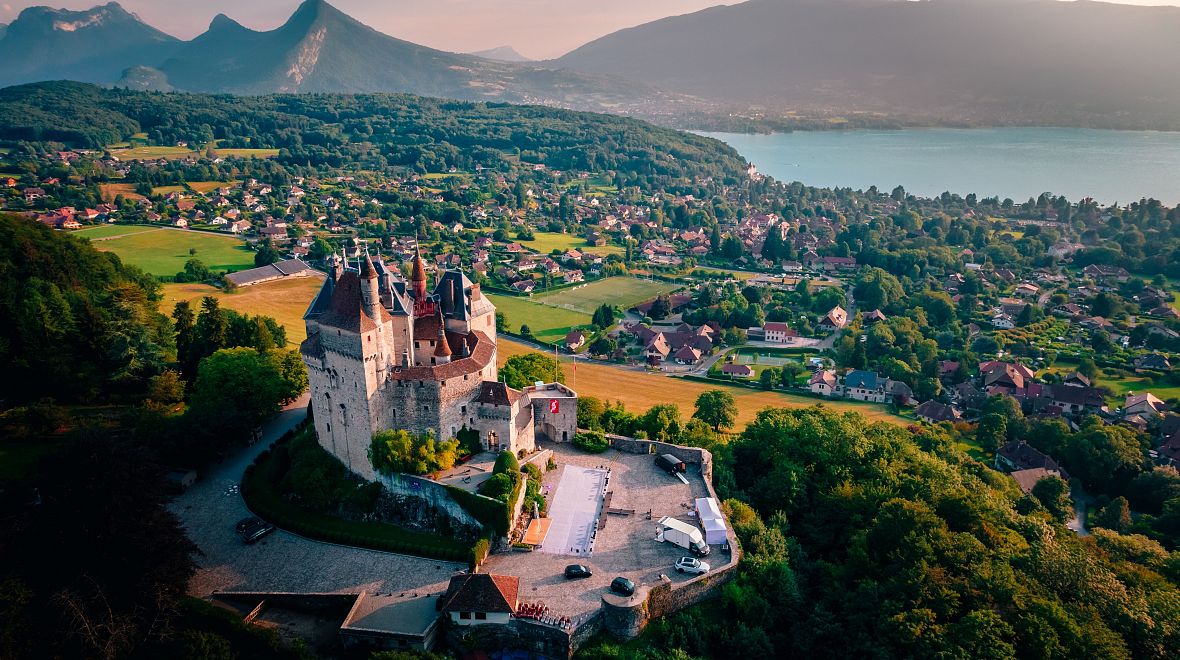 Letecký snímek hradu Menthon-Saint-Bernard s výhledem na město a jezero v Annecy