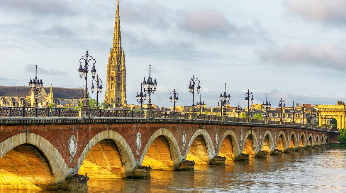 Most Pont de Pierre s oblouky a katedrálou Saint-Michel nad řekou Garonnou v Bordeaux
