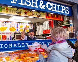 Usměvavý prodejce ve stánku s nejlepšími Fish and Chips v Londýně