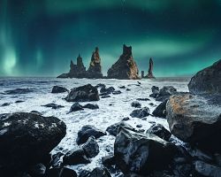 Polární záře nad útesy Reynisdrangar u polostrova Dyrhólaey