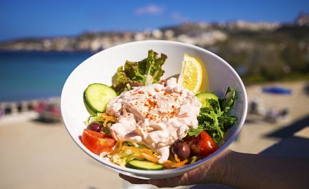 Lehké občerstvení na pláži v zátoce Mellieha Bay – čerstvý krevetový salát s okurkou, rajčaty, citronem…