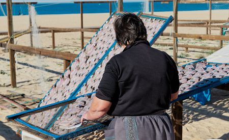 Žena v tradičním oděvu u sušení ryb v portugalském městečku Nazaré