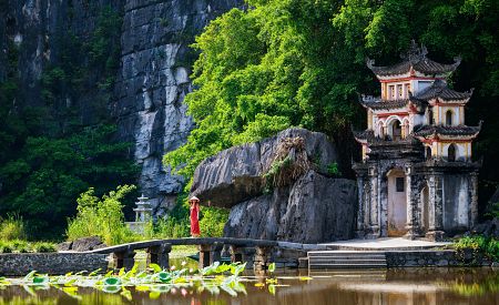 Starobylá pagoda Bich Dong zasazená mezi rýžová pole a vápencové skály