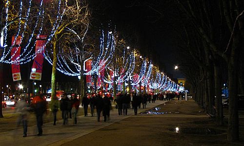Osvětlenou Champs-Éllysées prochází davy lidí.