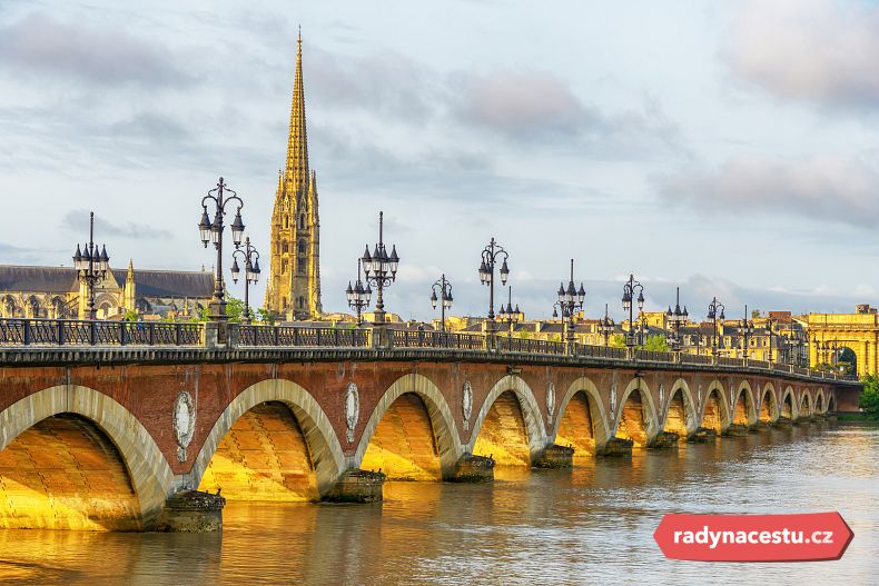Most Pont de Pierre s oblouky a katedrálou Saint-Michel nad řekou Garonnou v Bordeaux